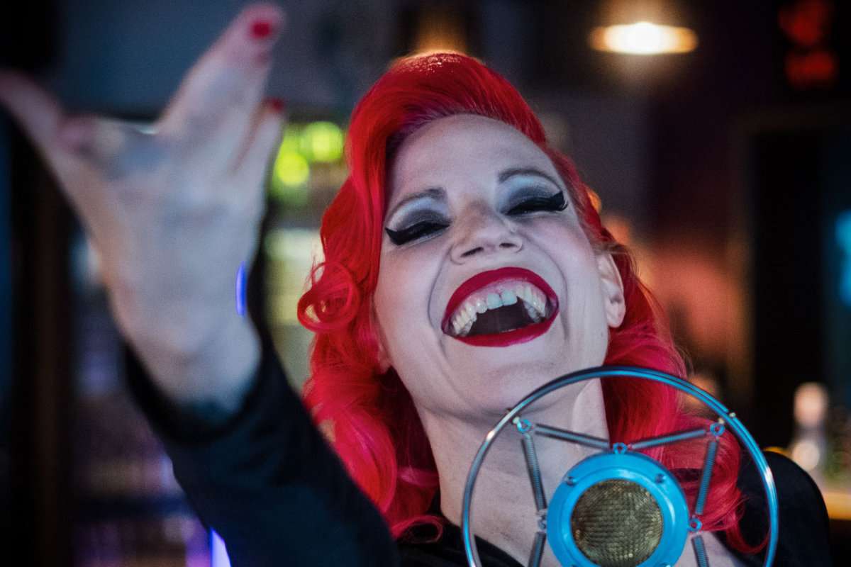 Foto der Sängerin, die Lieder von Edtih Piaf interpretiert. ROtes Haar, rote Lippen, rote Fingernägel